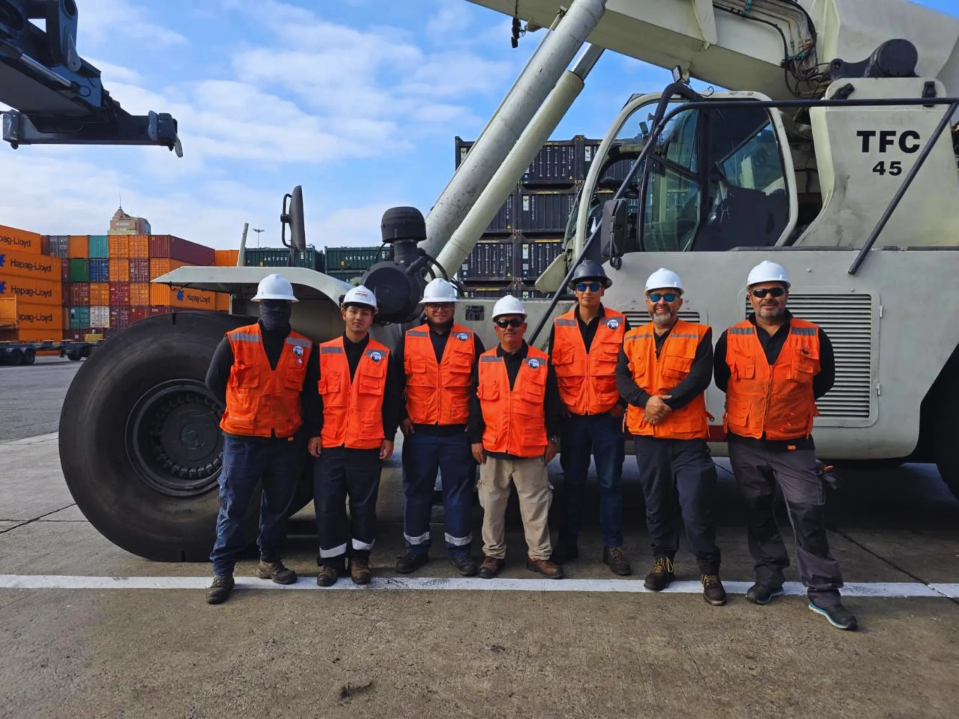 Equipo de Opazo Muellaje junto al reach stacker en el Puerto de Antofagasta